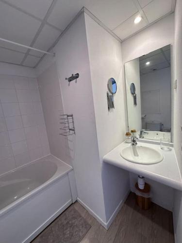 une salle de bain avec un lavabo, une baignoire et un miroir dans l'établissement Le Cocon - proche gare et centre ville, à Lourdes