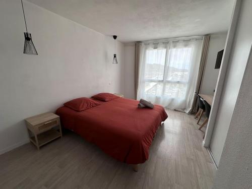 a bedroom with a red bed and a window at Le Cocon - proche gare et centre ville in Lourdes