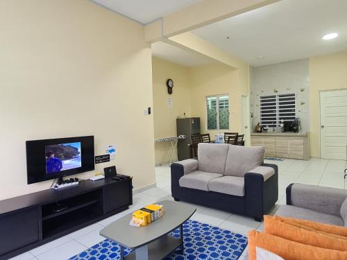 a living room with a couch and a tv at The Simplicity Homestay in Tanah Rata