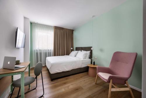 een hotelkamer met een bed, een bureau en een stoel bij Sirkin 16 Hotel - Autonomous hotel in Giv‘atayim