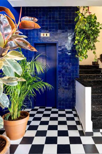 a room with a blue door and plants on a checkered floor at Sirkin 16 Hotel - Autonomous hotel in Giv‘atayim