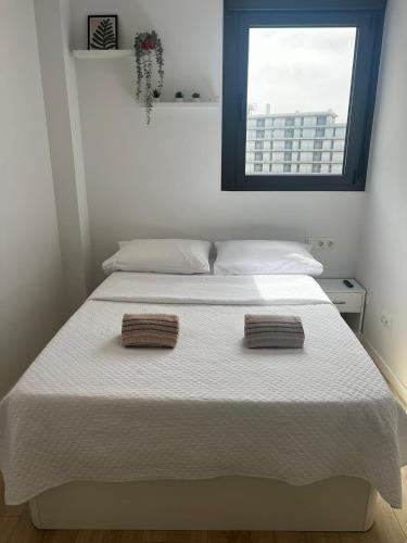 1 dormitorio con 1 cama blanca y 2 toallas en Habitación confortable para parejas, en Barcelona