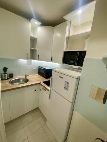 Il comprend une petite cuisine blanche avec un évier et un réfrigérateur. dans l'établissement F1 Nice Ouest, Terrasse vue mer, Wifi, à Nice