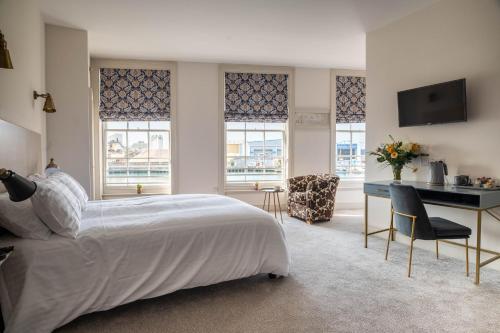 a bedroom with a bed and a desk and windows at The Old Custom House in Poole