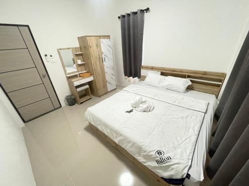 a bedroom with a bed with white sheets and pillows at บ้านพูลทรัพย์วิลเลจ POONSUB VILLAGe in Ban Na Charoen