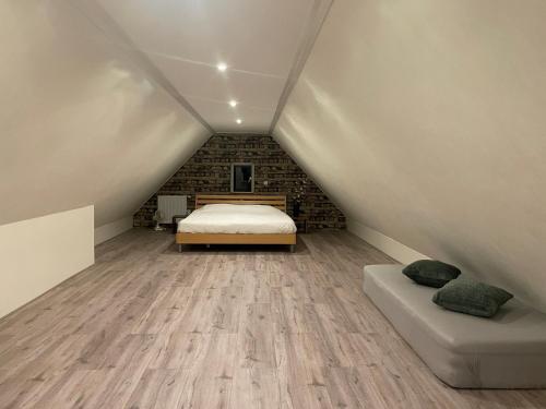 a attic bedroom with a bed and a couch at Hanendorper Hoeve - gastenhuisje bij monumentale boerderij in Emst