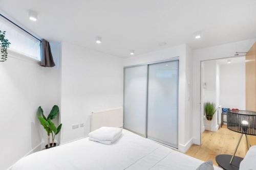 een witte slaapkamer met een bed en een glazen wand bij Bank/Monument apartment in Londen