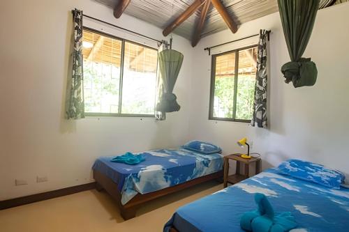 two beds in a room with two windows at Jungle Dreamz in Manzanillo