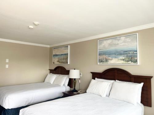 two beds in a hotel room with white sheets at Cape Cod Family Resort and Parks in West Yarmouth