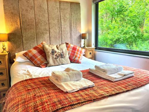 een slaapkamer met 2 handdoeken op een bed met een raam bij Arc Pod-HotTub-HuntersMoon-Warminster-Bath in Warminster