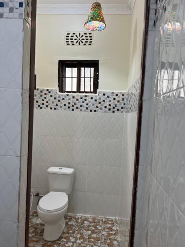 a small bathroom with a toilet and a window at Kilimanjaro Trekcity Hostel in Moshi