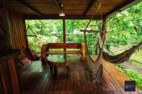 a porch with a hammock and a table and a swing at Cataratas Bijagua Lodge, incluye tour autoguiado Bijagua Waterfalls Hike in Bijagua
