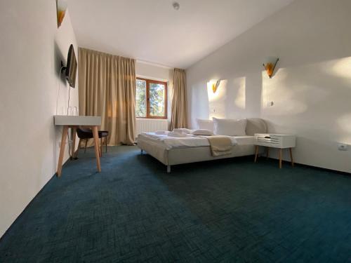 um quarto com uma cama, uma secretária e uma janela em Chalet Wiese em Poiana Brasov