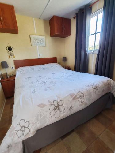 - une chambre avec un lit doté d'un couvre-lit blanc et de fleurs dans l'établissement Bungalow au milieu de la nature, à Junas