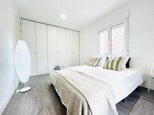 a white bedroom with a large bed and a window at Apartamentos dos Habs Madrid Urgel in Madrid