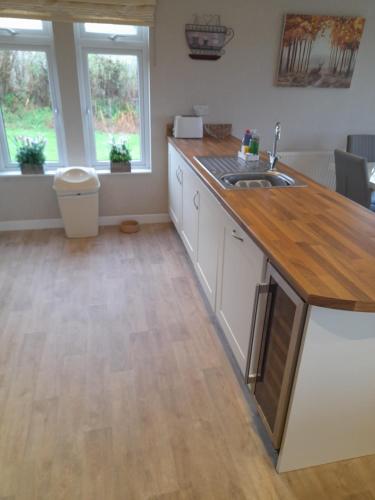 cocina con armarios blancos y encimera de madera en Devon Hills Holiday Park luxury timber lodge pet friendly with hot tub 2 to 6 guests, en Paignton