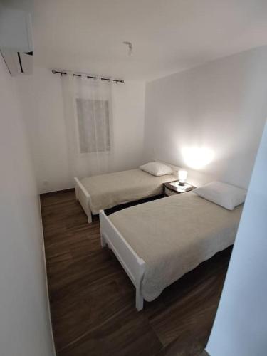 two beds in a white room with a mirror at Maison individuelle, à 5 km du Puy du Fou in Chambretaud
