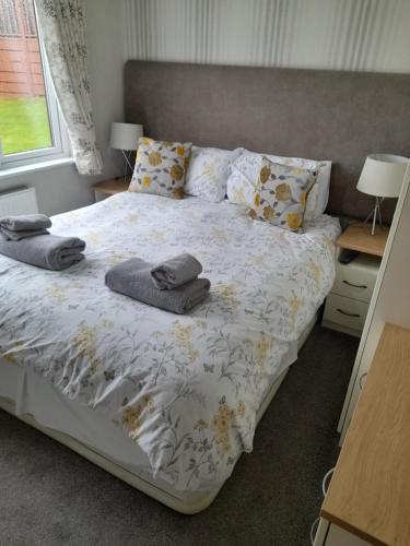 1 dormitorio con 1 cama con toallas en Devon Hills Holiday Park luxury timber lodge pet friendly with hot tub 2 to 6 guests, en Paignton