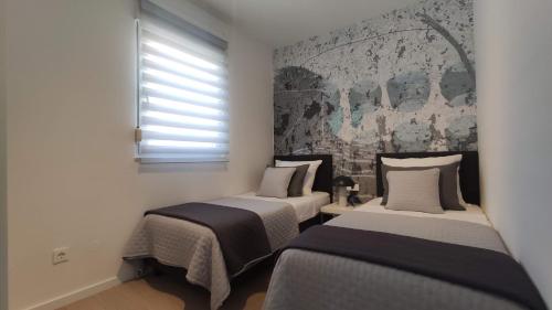 two beds in a small room with a window at Apartman Spalatum in Split