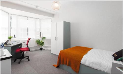 a bedroom with a desk and a bed with an orange blanket at Spacious room with shared facilities in London