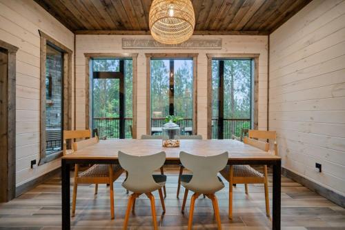 Un comedor con mesa y sillas de madera. en New Cabin w Hot Tub + Views Sleeps 12, en Broken Bow