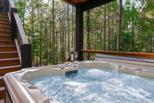 un jacuzzi en una terraza con árboles en New Cabin w Hot Tub + Views Sleeps 12, en Broken Bow