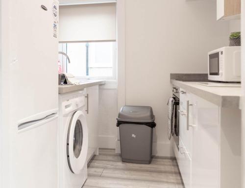 een witte wasruimte met een wasmachine en droger bij Castlemilk House in Glasgow