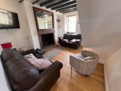 a living room with a leather couch and chairs at RB Contractor Stays - Ty Capel in Pwllheli