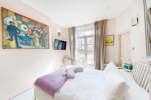 a bedroom with a white bed and a window at 1 Bed Maisonette with Garden - 1 min to station Share Save in London