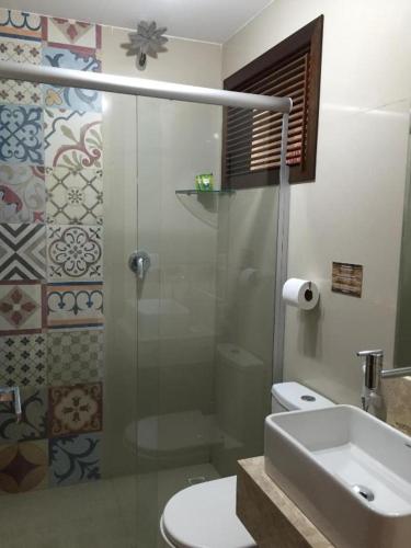 a bathroom with a shower and a toilet and a sink at Pousada Aconchego de Genipabu in Jenipabu