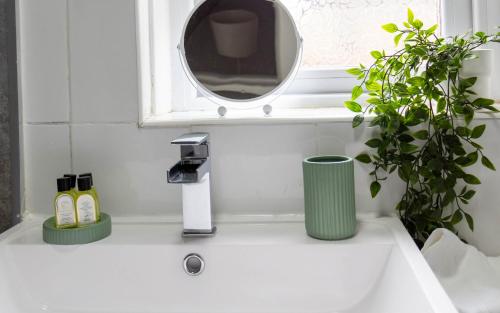 een wastafel in de badkamer met 2 planten en een spiegel bij Linwood House in Paisley