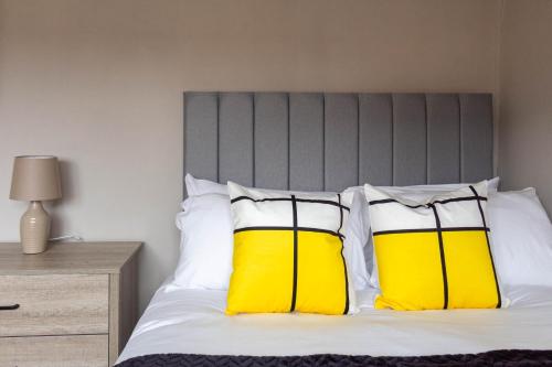 a bedroom with a bed with yellow and white pillows at Linwood House in Paisley