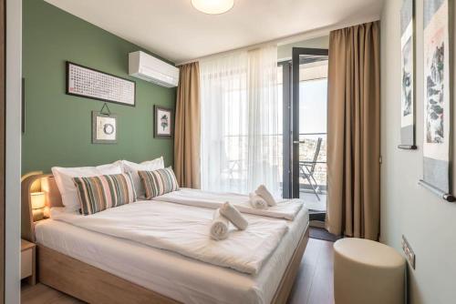 een slaapkamer met een groot bed met een groene muur bij Boho Beat Apartment in Varna