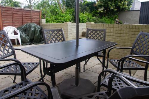 een tafel en stoelen met een parasol op een patio bij Spacious & bright 4-bedroom town-house with garden in Sydenham
