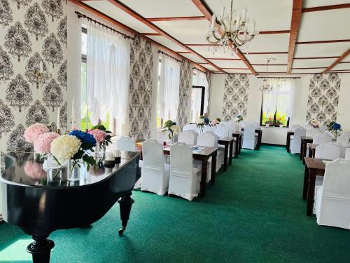 a banquet hall with tables and white chairs and flowers at Hotel Jef a Krčma u Rytíře in Doubice