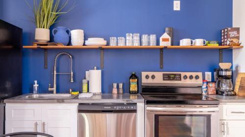 a kitchen with a stove and a sink and a blue wall at Central Urban Flat - Near the Best of Covington in Covington