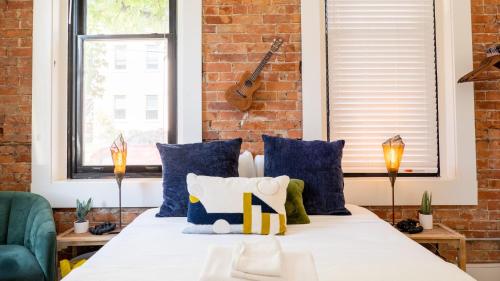 a bedroom with a bed with blue pillows and a brick wall at Central Urban Flat - Near the Best of Covington in Covington