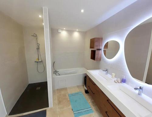 une salle de bain avec une baignoire, un lavabo et un miroir dans l'établissement La Molinière, belle demeure avec séjour cathédrale - La Molinière, beautiful residence with cathedral living room, à Les Montils