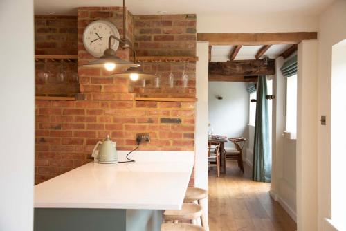 Mousehall Oast في Wadhurst: مطبخ بجدار من الطوب وساعة على الحائط