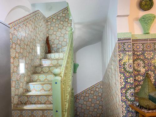 a staircase in a home with a mosaic wall at Dar Statia 4 vue mer cité portugaise in El Jadida