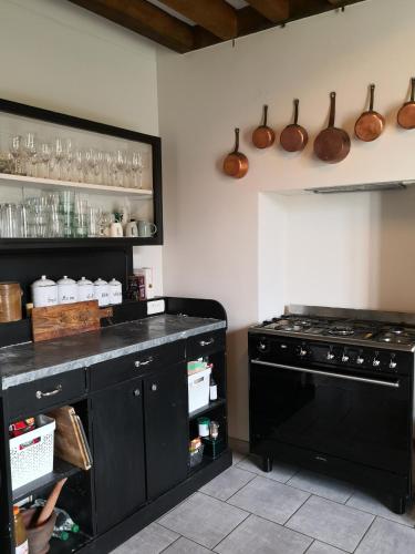 Il comprend une cuisine équipée d'une cuisinière et d'un comptoir noir. dans l'établissement Maison de famille piscine et vue, à Sougères-en-Puisaye