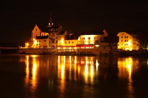 a city at night with lights on the water at la fontaine bénite in Seyssel