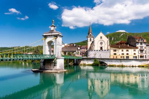 a bridge over a river in a town with a church at la fontaine bénite in Seyssel