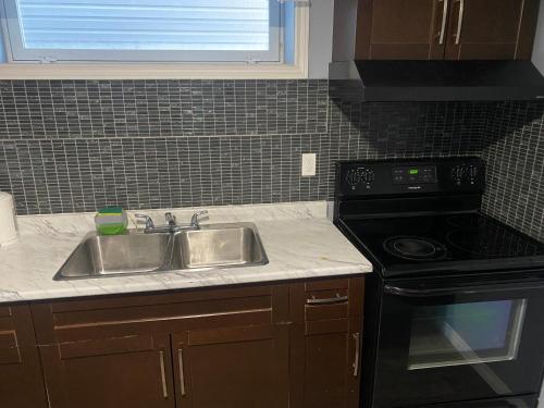 uma cozinha com um lavatório e um fogão em Cozy get-away suite em Regina