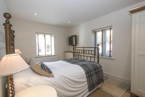 a bedroom with a bed and a lamp and windows at Black Lion Court in Little Walsingham