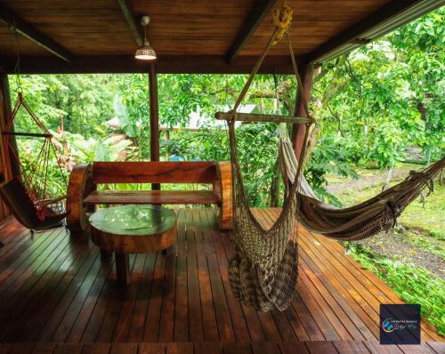 una hamaca en una terraza con un banco y una mesa en Cataratas Bijagua Lodge, incluye tour autoguiado Bijagua Waterfalls Hike, en Bijagua