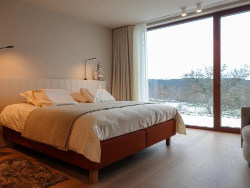 ein Schlafzimmer mit einem großen Bett und einem großen Fenster in der Unterkunft Villa La Verdoyante in Lierneux