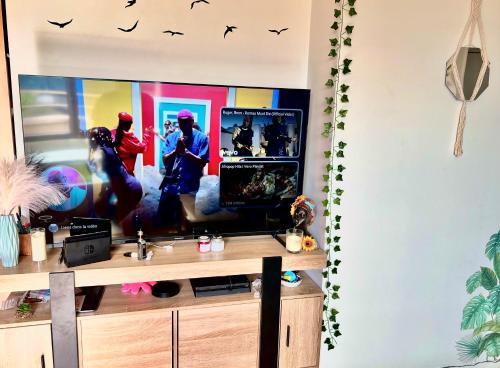 a living room with a flat screen tv on a desk at Comme à la maison 10mn du Stade de France in Aubervilliers