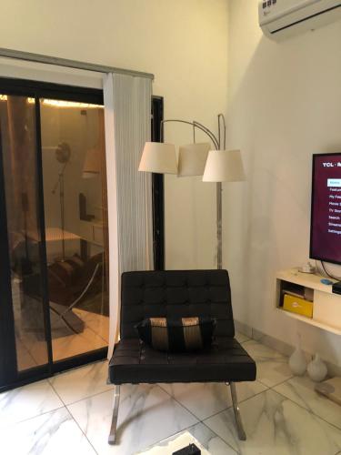 einen schwarzen Ledersessel in einem Wohnzimmer mit einem TV in der Unterkunft Wang Residece in Lomé