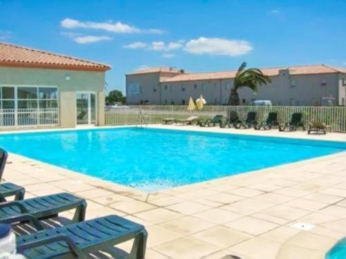 a large blue swimming pool with two blue chairs at Hôtel Jasses de Camargue in Gallargues-Le-Montueux